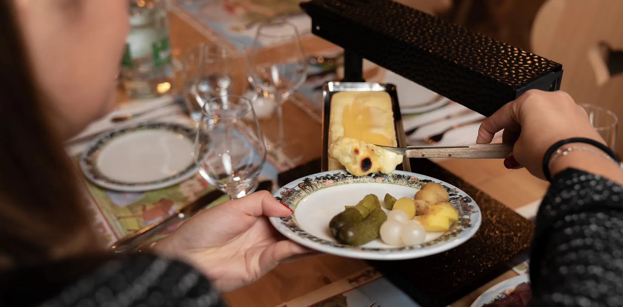 Assiette de raclette, pommes de terre et cornichons servie à table